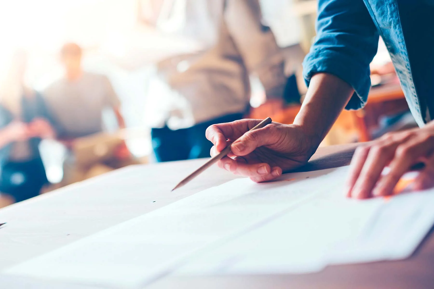Person arbeitet an einem Designentwurf mit Farbfächern und Druckvorlagen